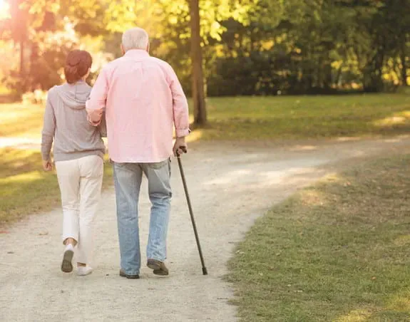 A woman and an elderly man walking with a cane.