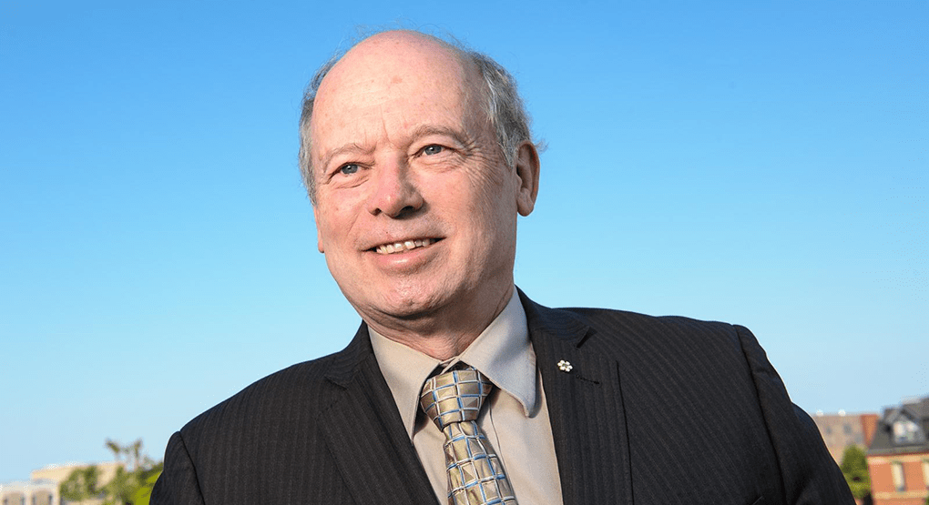 A headshot of Dr Patrick McGrath, a man with fair skin and grey hair wearing a suit jacket, shirt and tie