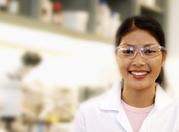 Two cancer researchers wearing lab coats and safety glasses