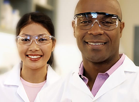 Deux chercheurs sur le cancer portant des blouses de laboratoire et des lunettes de sécurité