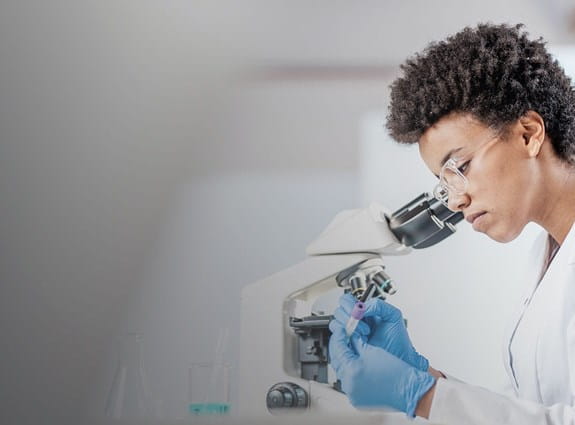 Researcher looking into a microscope in a laboratory setting