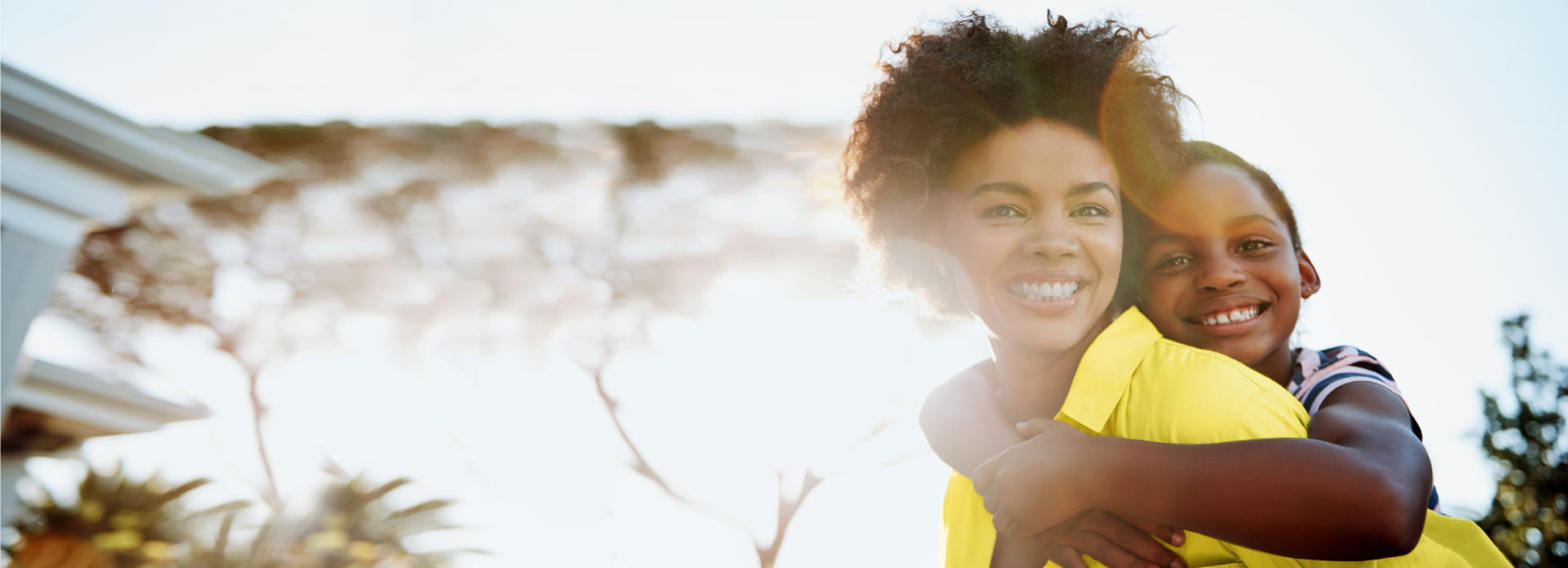 Femme portant son fils sur ses épaules et souriant à la caméra.