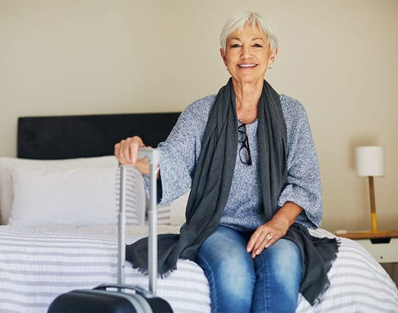 A person sitting on a bed with their luggage