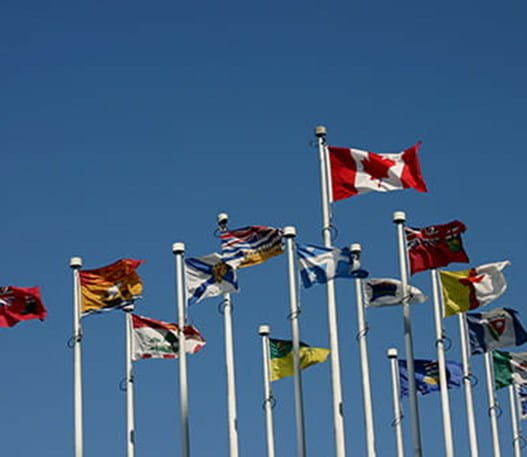 Drapeaux du Canada et des provinces flottant sur des mats.