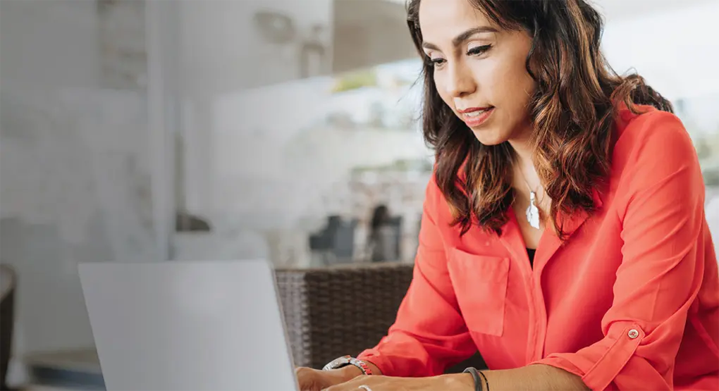 A woman sits on a couch working on her laptop