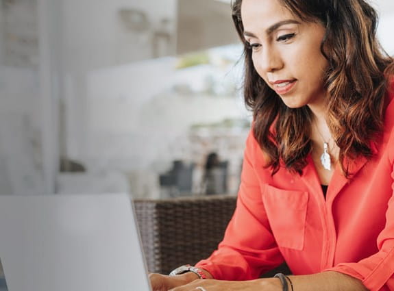 A woman sits on a couch working on her laptop