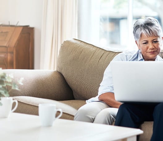 A couple on a couch looking at a laptop together