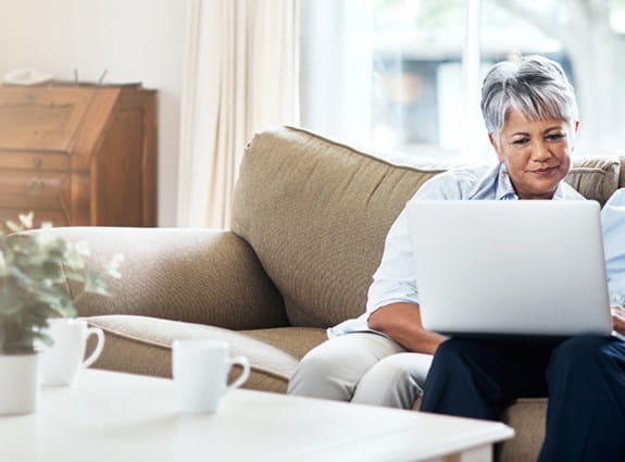 A couple on a couch looking at a laptop together