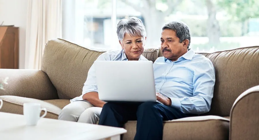 A couple on a couch looking at a laptop together