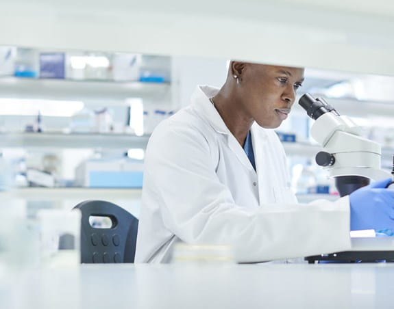 Scientist looking under a microscope in a lab