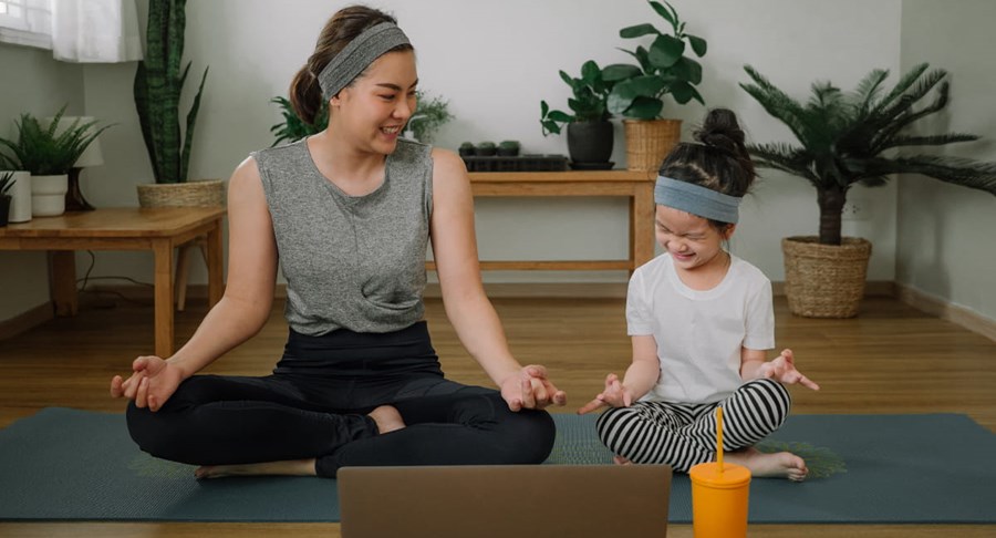 Une mère et sa fille assises les jambes croisées sur un tapis de yoga