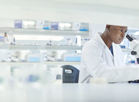 Scientist looking under a microscope in a lab