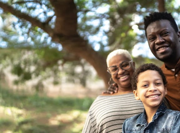 Three adults and a child smiling outdoors