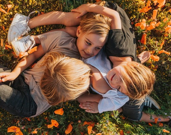Three young boys are playing together on a grassy field