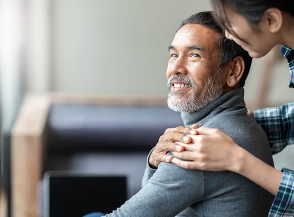 A man is looking back and smiling at a woman who has her hand on his shoulder