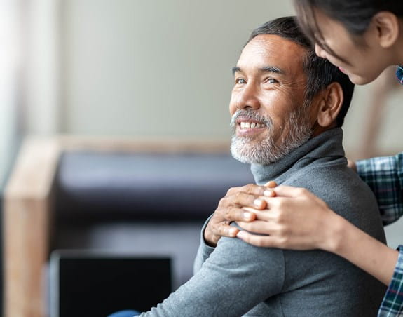 A man is looking back and smiling at a woman who has her hand on his shoulder