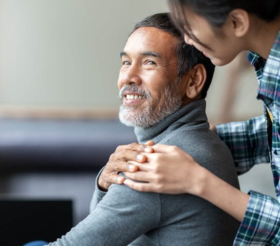 A man is looking back and smiling at a woman who has her hand on his shoulder