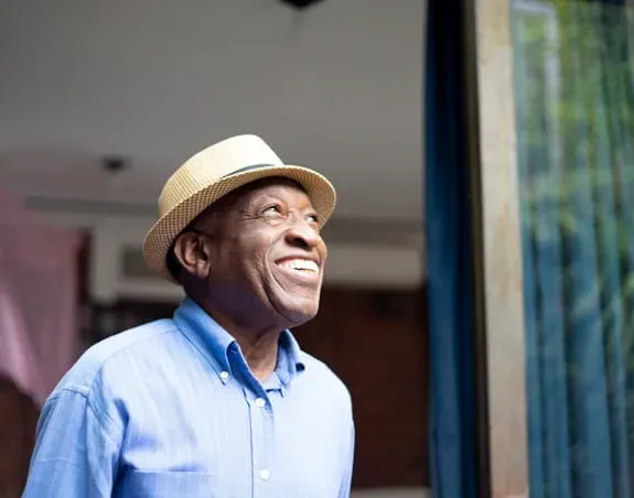 Man wearing a hat and blue shirt looking up and smiline