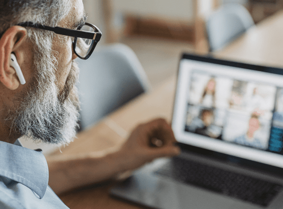 an over the shoulder look at a man who is looking at his laptop