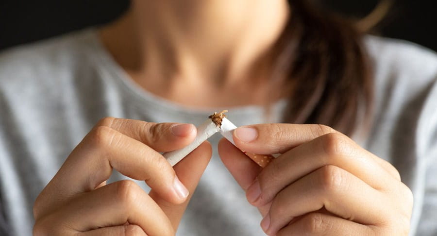 Une femme cassant une cigarette en deux.