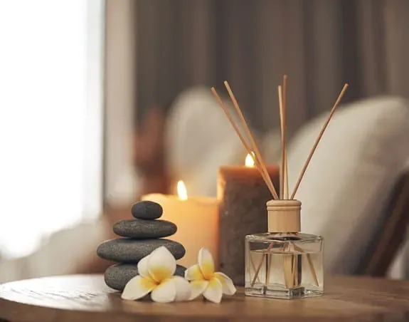 Candles, a diffuser and therapy stones on a coffee table.