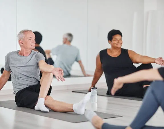 A group of men and women in a yoga classroom.