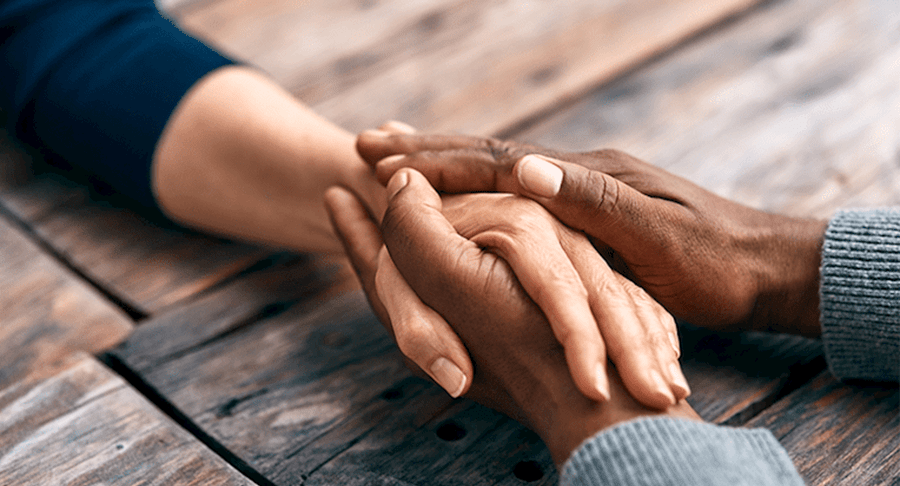 An individuals hand is being embraced by the hands of another person