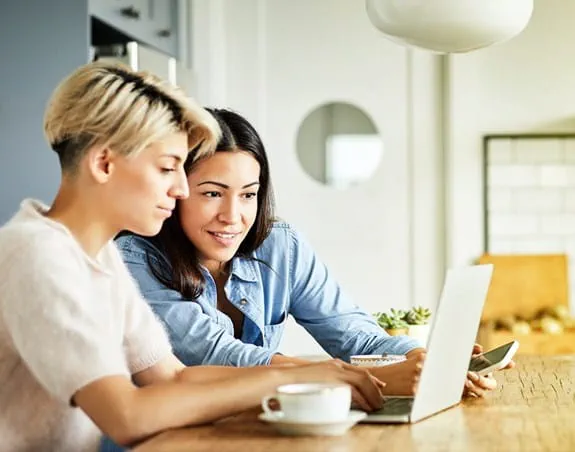 Two women sitting together looking at a computer screen