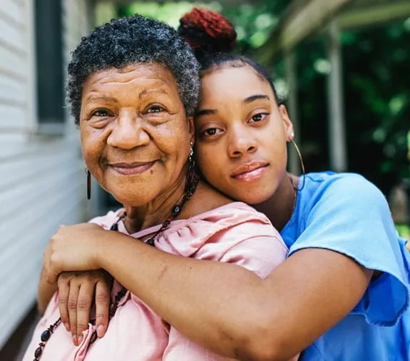 granddaughter embraces her grandmother, grandmother is smiling