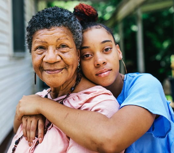 granddaughter embraces her grandmother, grandmother is smiling