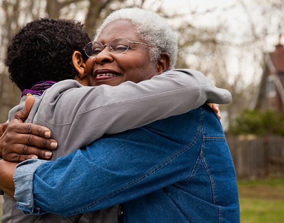 A mother hugs her adult daughter.