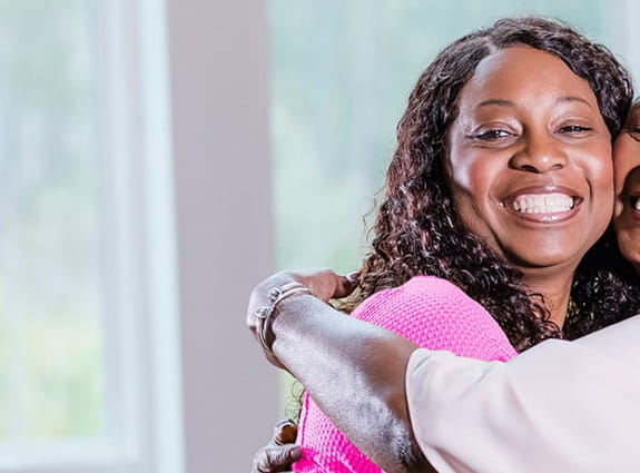 Two happy women hug each other smiling