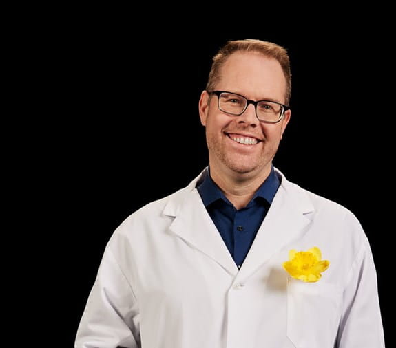 Trevor Pugh, Ph. D., chercheur subventionné par la Société canadienne du cancer, avec une jonquille sur son sarrau de laboratoire.  
