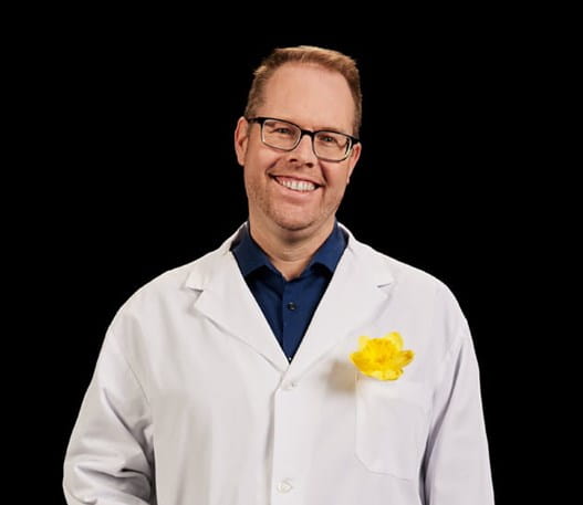 Dr. Trevor Pugh, a Canadian Cancer Society funded researcher, with a daffodil in his lab coat.