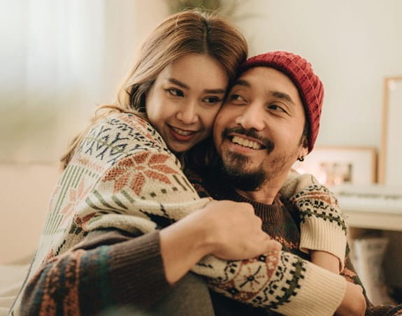 Un jeune couple s’étreignant en souriant