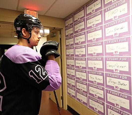 A hockey player looks at cards with the words ‘I fight for’ and a person’s name.