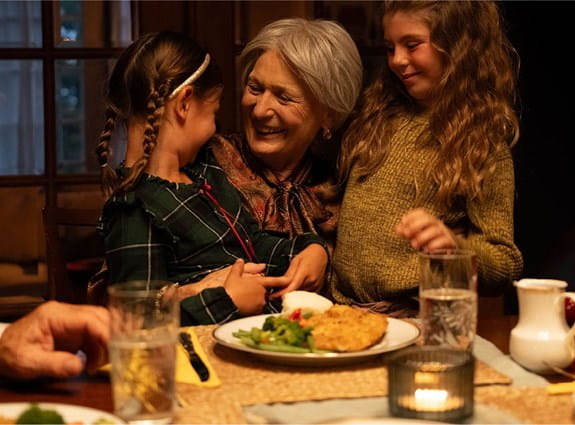 A smiling woman is hugging children.