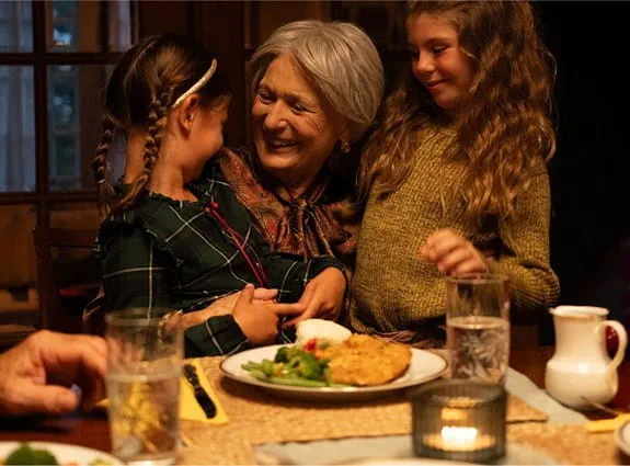 A smiling woman is hugging children.
