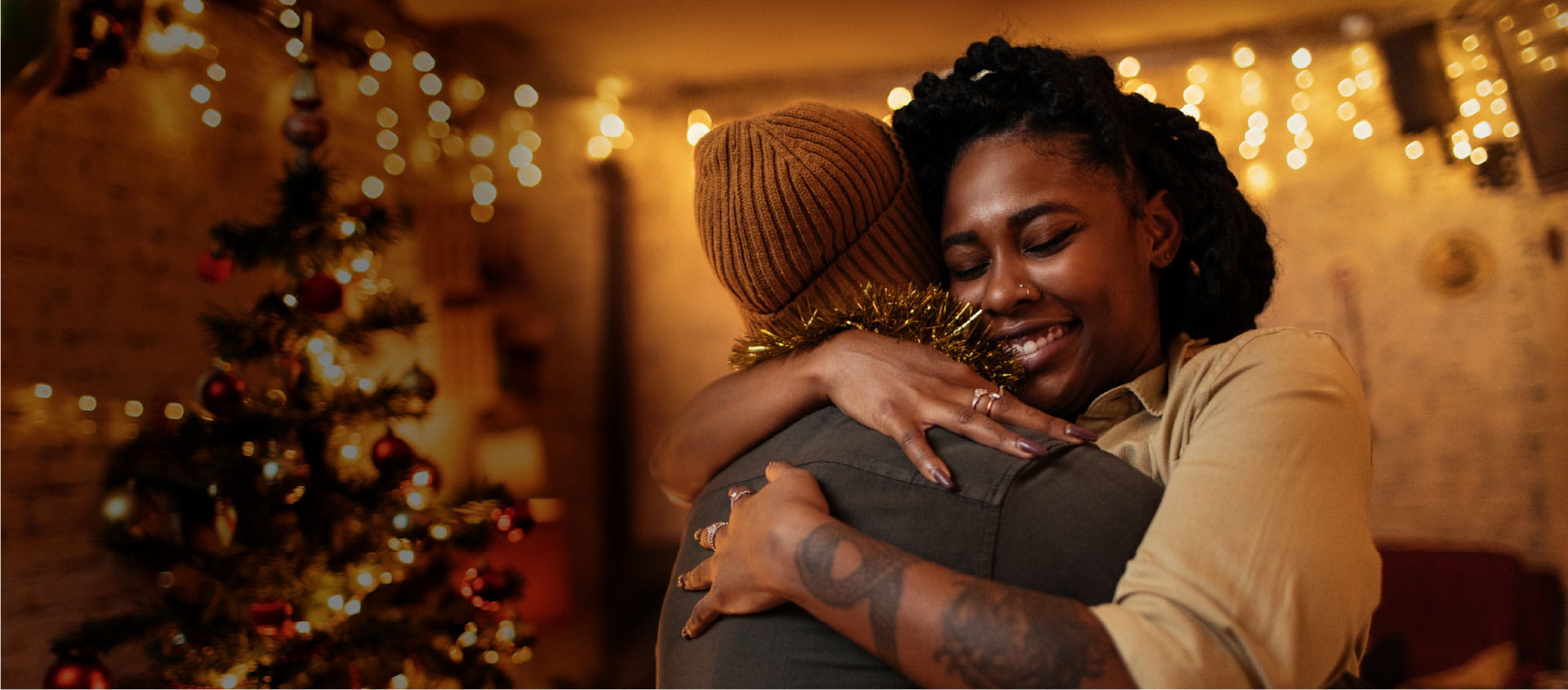 Une femme étreignant quelqu’un qui porte une casquette brune.