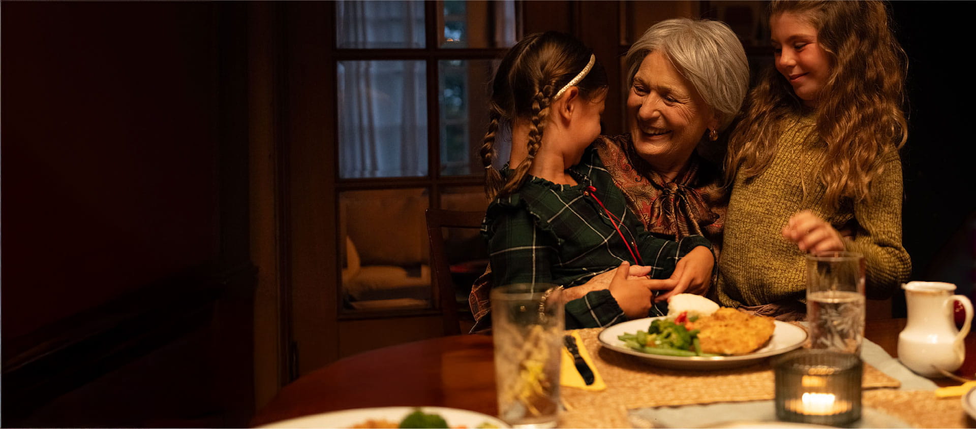 Une femme sourit en serrant deux enfants dans ses bras. 