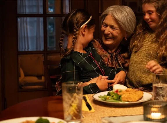 A smiling woman is hugging children.