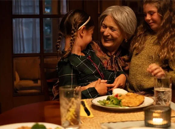 Une femme sourit en serrant deux enfants dans ses bras.