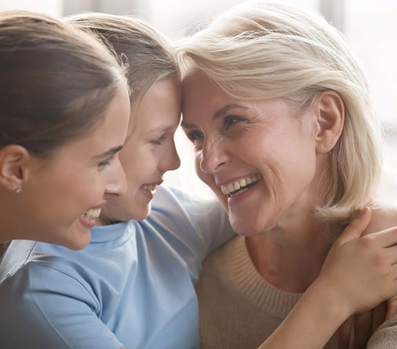 A grandmother smiling with her two young granddaughters