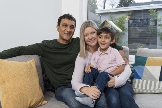 Kathy Andrews sitting on a sofa with her husband and young son 