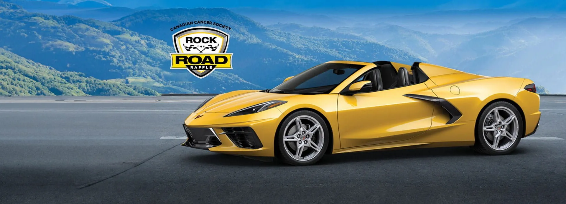 Chevrolet Corvette Stingray jaune sur une route avec un arrière-plan pittoresque