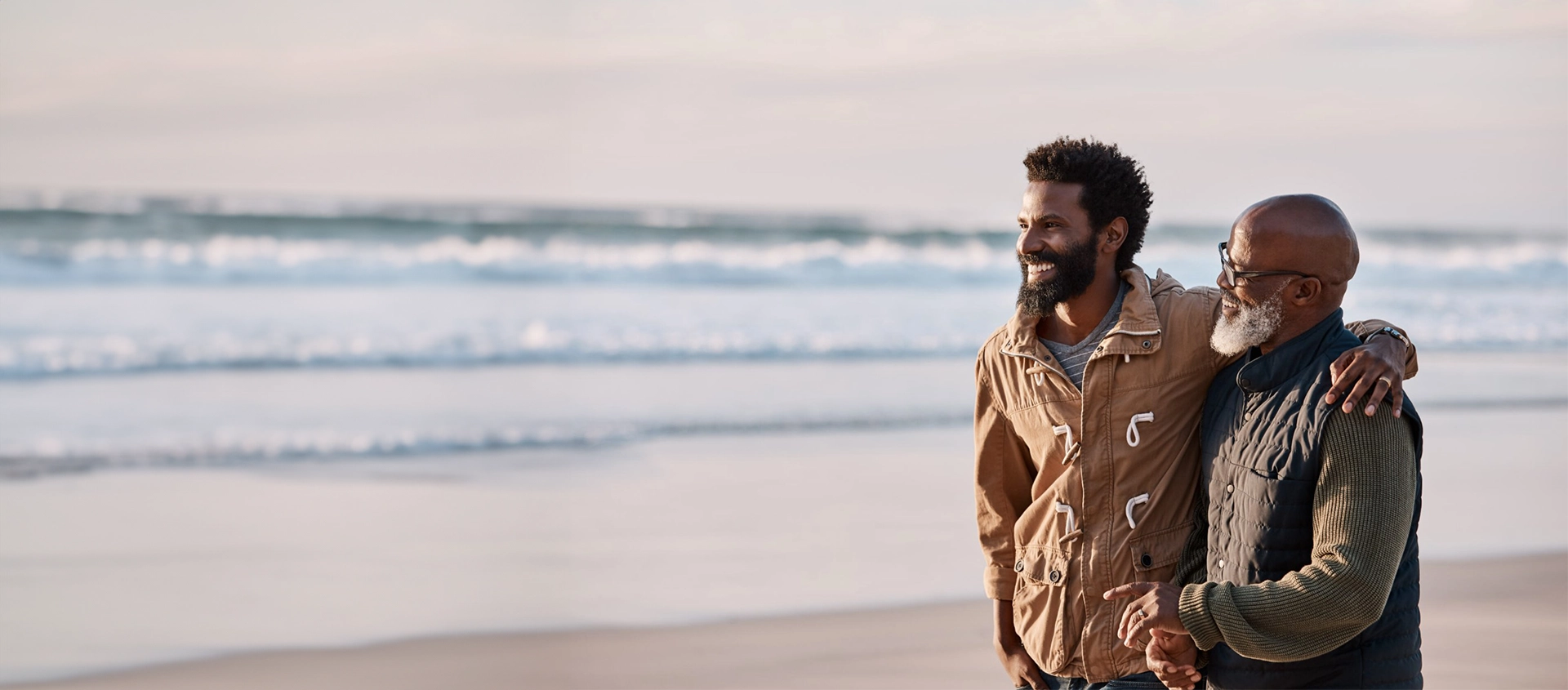 Deux hommes d’âge moyen qui se sourient sur une plage.
