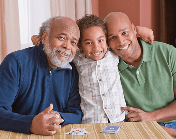 A young boy puts his arms around his father and grandfather.