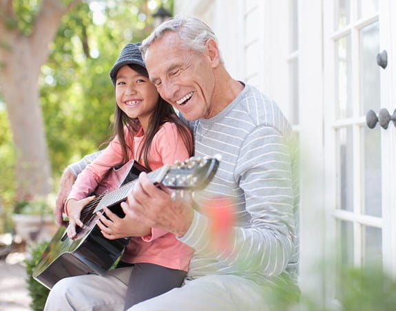 A man plays guitar with his granddaughter.