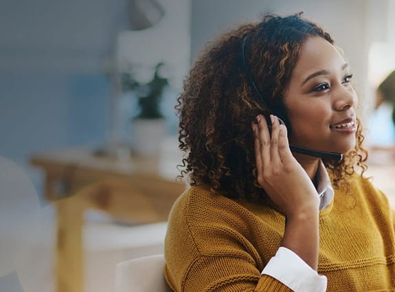 Woman wearing a headset in an office and smiling.