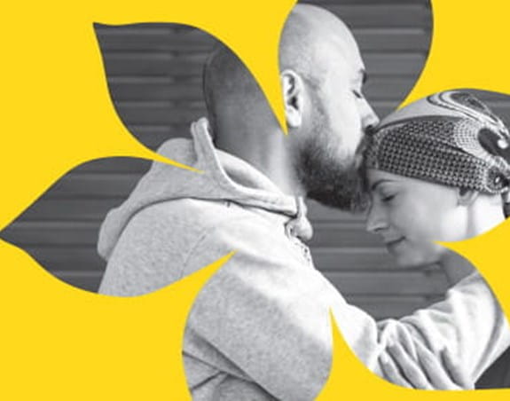 A man kissing the forehead of a female cancer patient.
